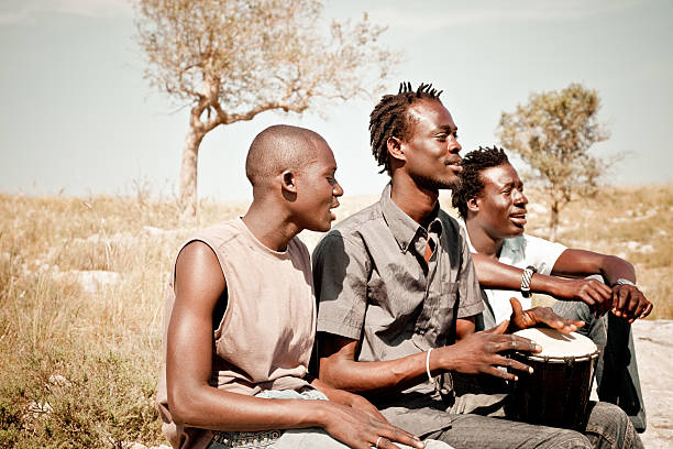 três africanos homens jogando djembe no meadow - rural africa - fotografias e filmes do acervo