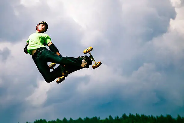Mountain boarder jumping against cloudy sky. Big air backside grab.