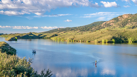 summer morning on Horsetooth Reservoir at foothills of Rocky Mountains in northern Colorado with a fishing boat and a stand up paddler, popular recreation destination in Fort Collins area