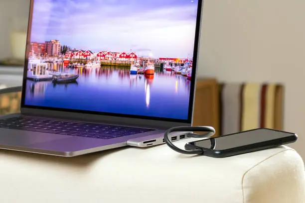 Smartphone is being charged connected to a hub adapter on a laptop.