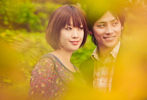 Horizontal portrait of a beautiful, young Japanese couple standing amongst an Autumn scenery. Images with photographed in Tokyo, Japan.