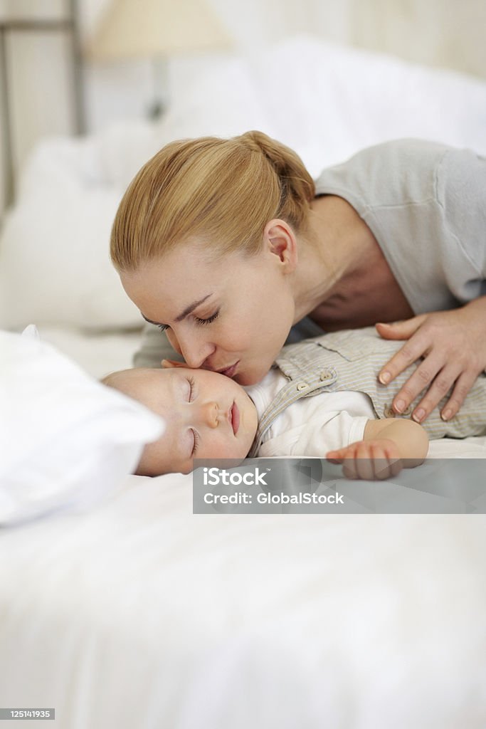 Mother kissing sleeping baby Portrait of loving mother kissing sleeping baby 30-39 Years Stock Photo