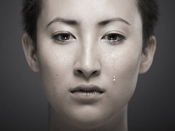 portrait of young asian girl with tear rolling down cheek - huilen stockfoto's en -beelden