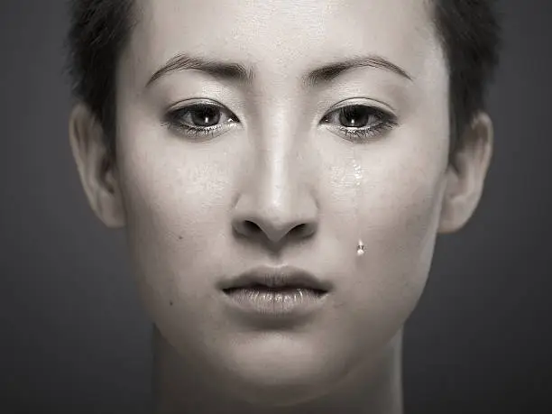 Photo of Portrait of young Asian girl with tear rolling down cheek