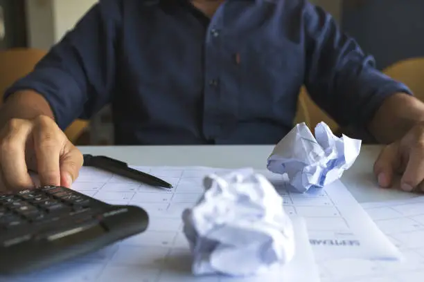 Photo of Closeup of crumpled paper on table with unhappy businessman lack of ideas. soft-focus and over light in the background