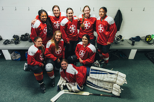 Portrait of a women's hockey team dressed up in their recreation league uniforms. They are posing in the female locker room before their game. Image taken in Utah, USA.