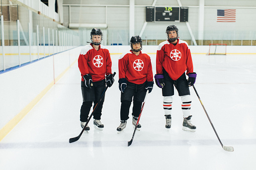 Portrait of three women's ice hockey offense players before a recreation league hockey game. They are on the ice ready to play their game. Image taken in Utah, USA.