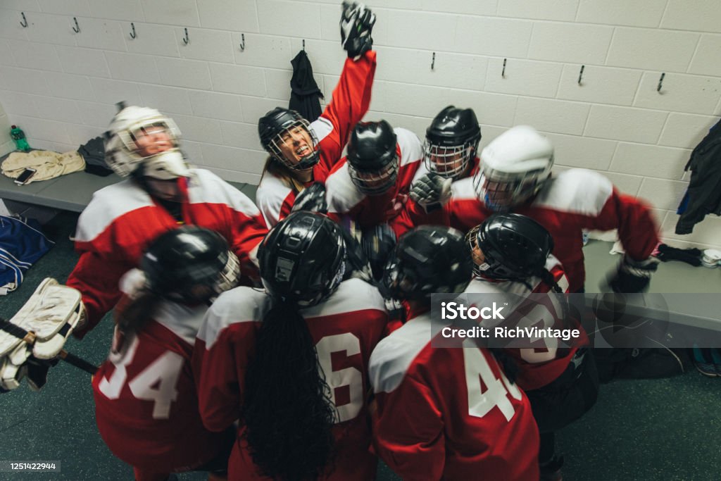 Women's Ice Hockey Team Celebrates Portrait of a women's hockey team in the locker room celebrating after a hard fought victory. are are doing a team cheer.. Image taken in Utah, USA. Locker Room Stock Photo