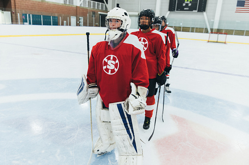 Portrait of a women's hockey team dressed up in their recreation league uniforms. The goalie waits in line to greet the other team post game. Image taken in Utah, USA.