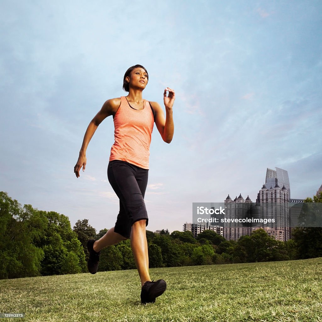 Woman Running in Piedmont Park on Grass Field Woman running in Piedmont Park located in Atlanta, Georgia USA African-American Ethnicity Stock Photo