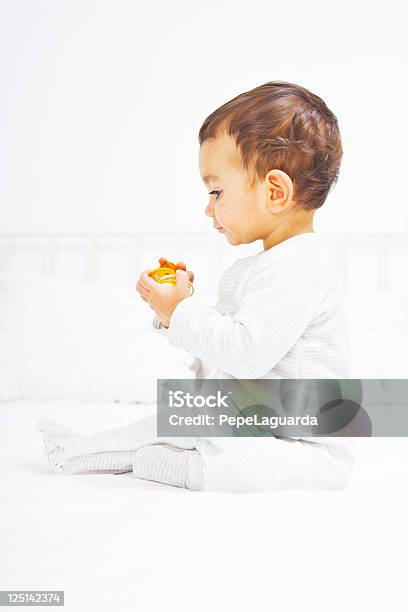 Bebê Na Cama A Brincar Com Chupeta - Fotografias de stock e mais imagens de 12-23 Meses - 12-23 Meses, Almofada - Artigo de Decoração, Amarelo