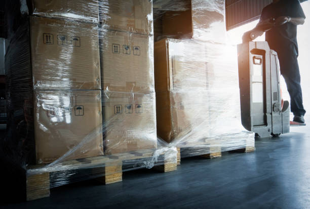 istock Warehouse worker driving electric forklift pallet jack unloading shipment pallet goods. 1251424901