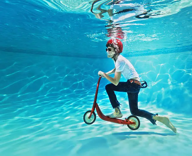 Photo of teenager pushing a scooter underwater