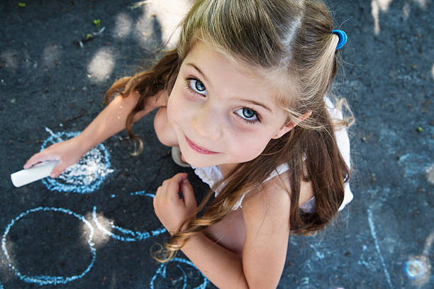 niño dibujo sobre el pavimento de una entrada del hotel. - little girls sidewalk child chalk fotografías e imágenes de stock