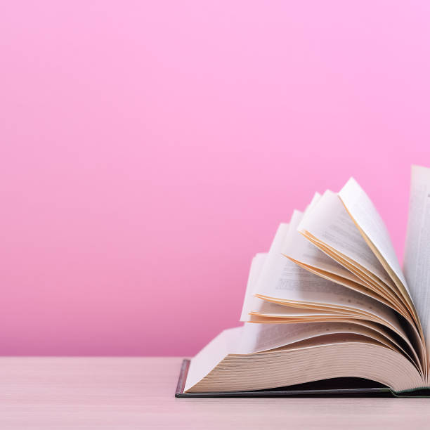 istock The book is open, lying on the table, sheets fanned out on a pink background. 1251432228