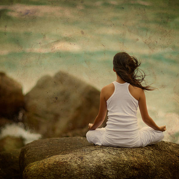 Woman Meditating by the Ocean stock photo