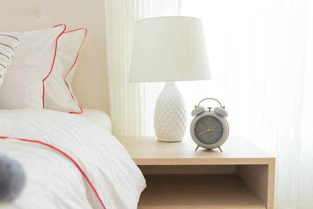 istock Alarm clock on the table beside white cozy bed in bedroom. 1251436633