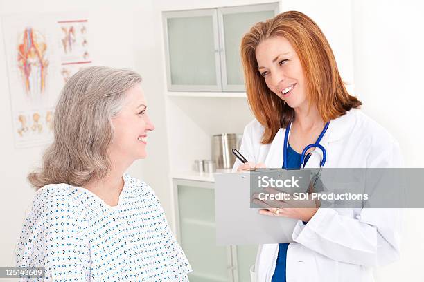 Uśmiechający Się Lekarz Notatek I Komunikowania Się Z Szczęśliwy Pacjenta - zdjęcia stockowe i więcej obrazów Aktywni seniorzy