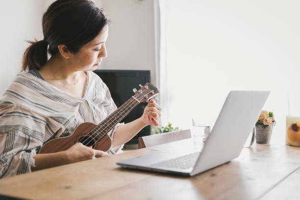 istock Woman playing ukulele at home 1251436950