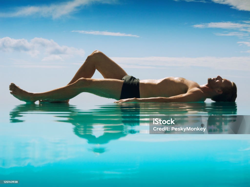 Tranquilo Man Lying que reflejan en la piscina de borde infinito - Foto de stock de Acostado de espalda libre de derechos