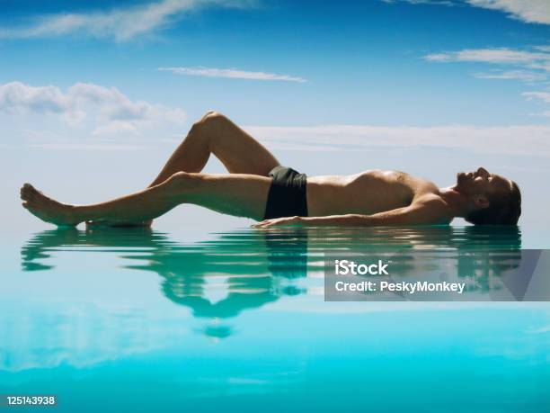 Foto de Homem Relaxante Deitar Refletindo Na Piscina De Borda Infinita e mais fotos de stock de Corpo inteiro