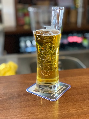 Pilsen, Czech Republic - July 22, 2015: Glass of Pilsner Urquell Beer with condensed water and logo on glass. Pilsner Urquell, the first pilsner beer in the world, known better by its German name Pilsner Urquell is a prominent brand of the global brewing company SABMiller.
