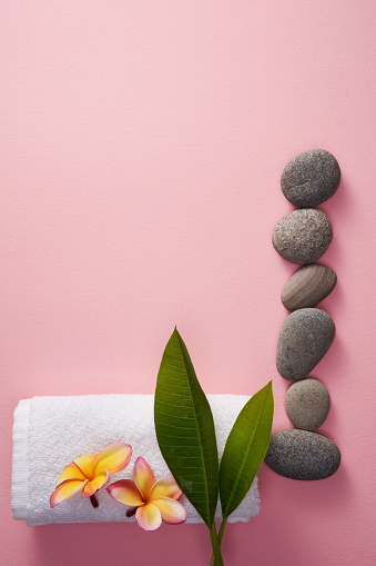 frangipani flowers and row of stone on pink background