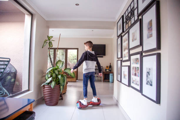 A Nine-year-old boy riding his motorized hoverboard at home. A Nine-year-old boy riding his motorized hoverboard in the hallway at home. hoverboard stock pictures, royalty-free photos & images