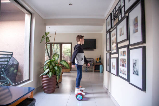 A Nine-year-old boy riding his motorized hoverboard at home.