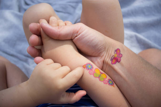 Mother and daughter holding hands Mother and daughter with temporary tattoos, stickers, holding hand, summer temporary stock pictures, royalty-free photos & images