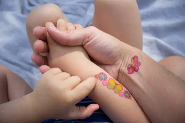 Mother and daughter with temporary tattoos, stickers, holding hand, summer