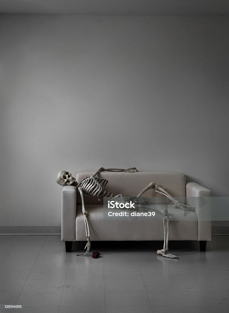 skeleton on a couch A skeleton lies neglected on a couch. A rose lies on the floor. Human Skeleton Stock Photo