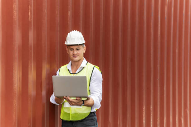 istock caucasian white businessman or engineer control worker working on digital laptop computer with cargo containers in background at container cargo harbor, industrial, logistic import and export concept 1251443651