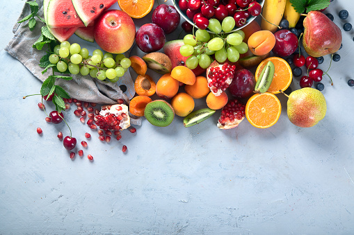 Fresh healthy fruits on grey background. Foods high in antioxidants, carbs,  minerals and  vitamins. Food for immune boosting. Top view with copy space