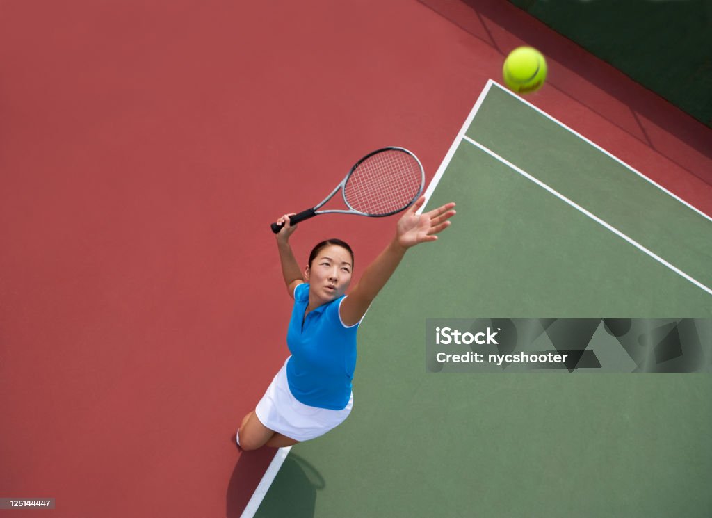 woman tennis player serving Young Asian woman serving tennis ball, photographed from directly above her.  Tennis Stock Photo