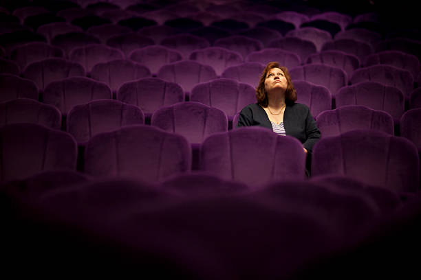 The Show Must Go On a woman sitting in the theater - she looks up - selctive focus on women concert hall stock pictures, royalty-free photos & images