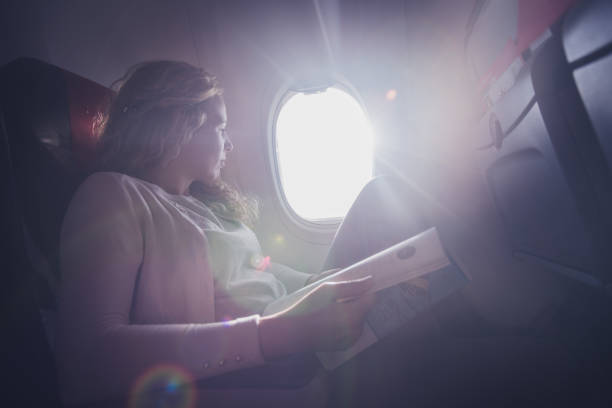 istock Curly woman reading newspaper in airplane. 1251446406