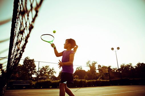Little girl learning to play tennis.