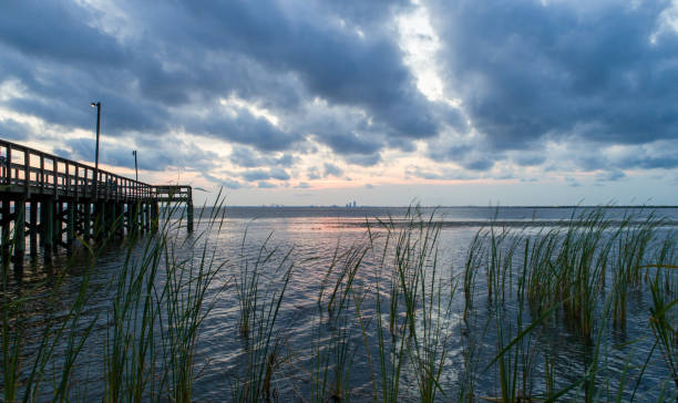 Overcast sunset on Mobile Bay, Alabama Sunset over Mobile Bay on the Alabama Gulf Coast afted a summer storm mobile bay stock pictures, royalty-free photos & images
