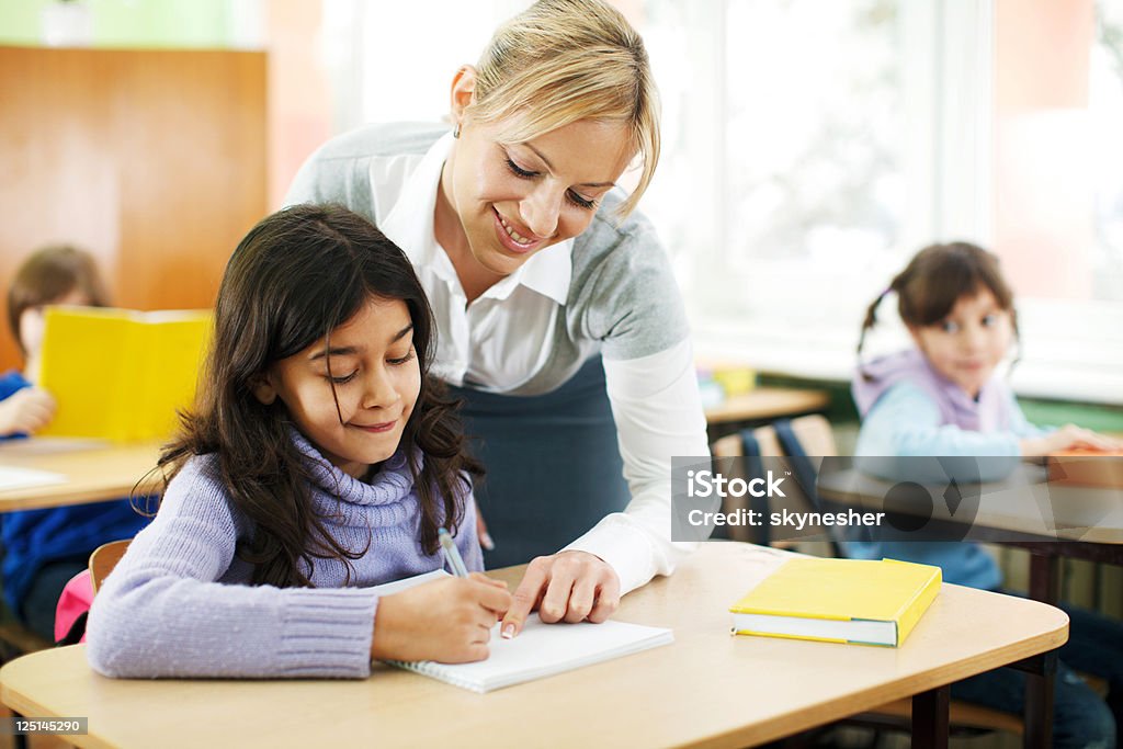 Profesor explicando tareas a una niña en edad escolar - Foto de stock de Maestro libre de derechos