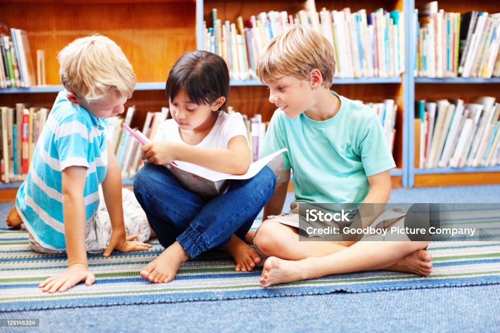 Linda chica escrito en el libro con los niños mirando a su - Foto de stock de Actividad libre de derechos