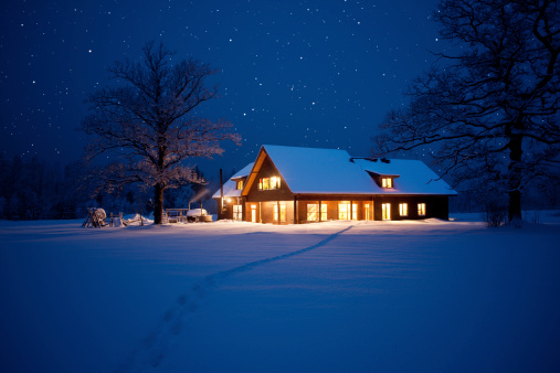 Illuminated house in wintery scene with footpath to it.