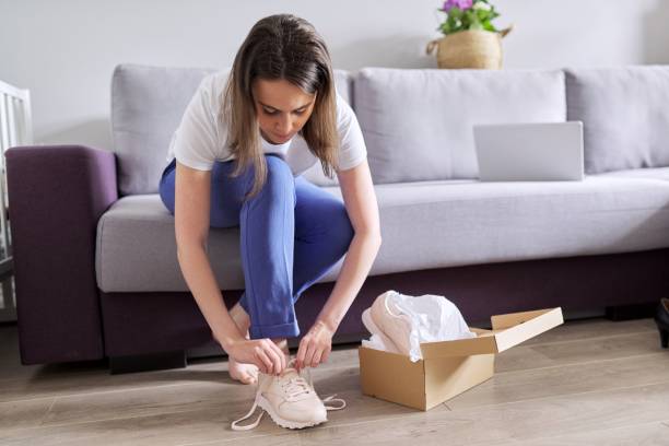 Young woman shoes new sneakers, box with sneakers at home background Young woman shoes new sneakers, box with sneakers at home background. woman legs open stock pictures, royalty-free photos & images