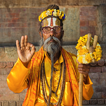 Jaipur, Rajasthan, India - Holy man in guru outfit posing for tourists for money