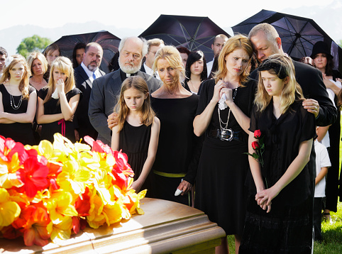 A mother and two children standing graveside at a funeral.