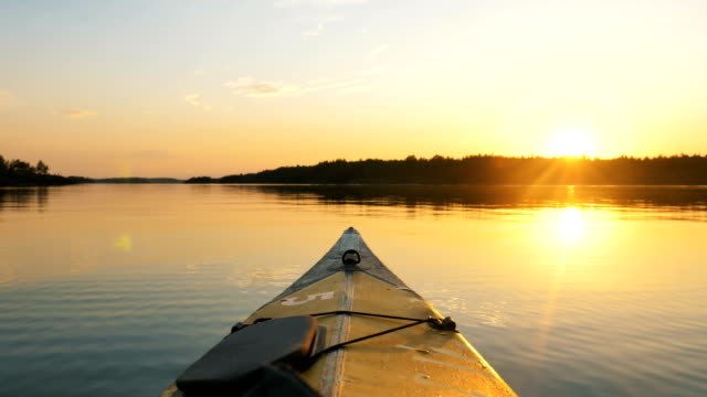 bow of kayak floats on calm surface of twater at sunset in Golden hour, outdoor activities