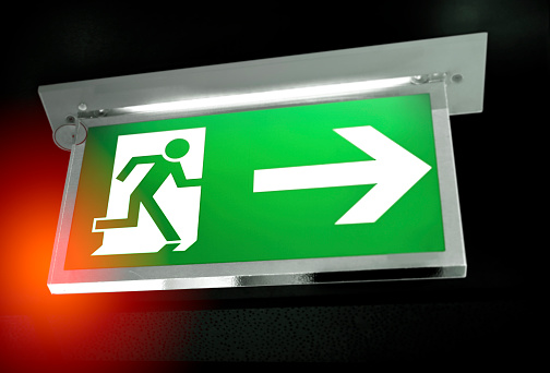 Modern green emergency exit sign on black background