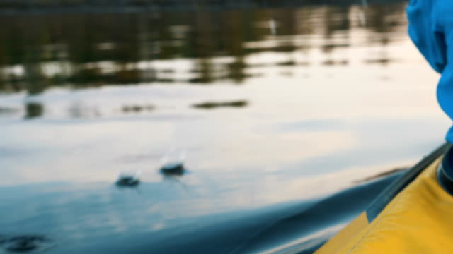 man paddles a kayak on the lake at sunset, close-up