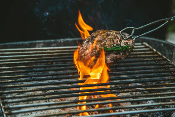 barbecue heißes gegrilltes fleisch mit feuer flamme hitze grill kochen abendessen brennen aus holzkohle. gebratenes steakgrillen mit feuer und rauchen im freien. rindfleisch grillen im freien für party. westliches lebensmittelkonzept - pork tenderloin dinner barbecue stock-fotos und bilder