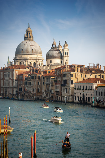 View on Grand Canal (Canal Grande) with gondola boats on the water. Beautiful old buildings along the waterfront. Dome of Basilica in the background. Venice, Italy. Copy space